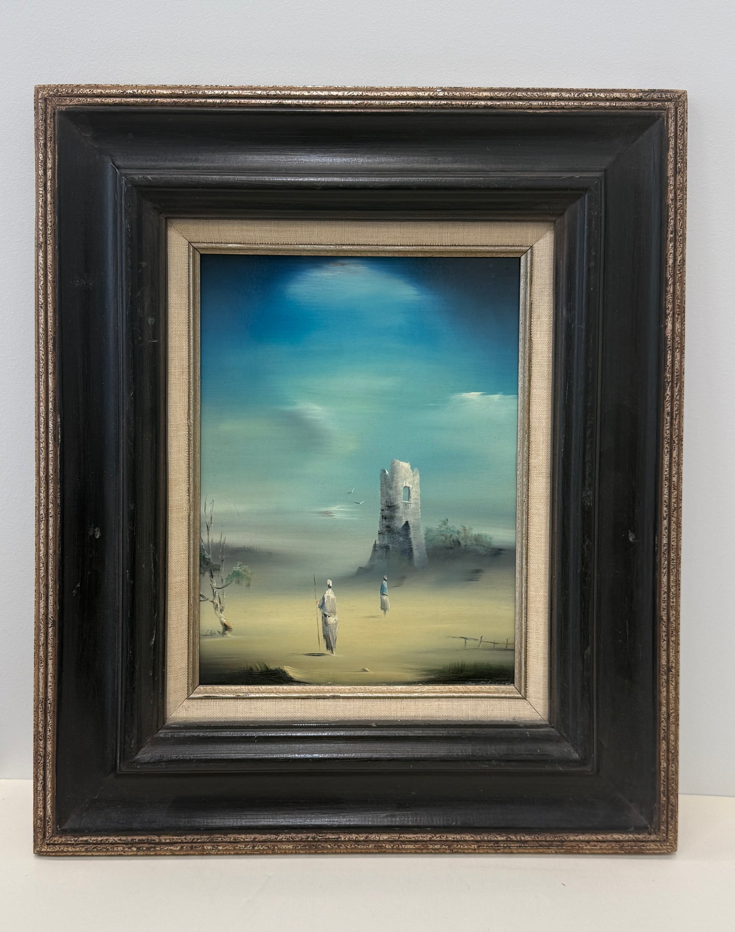 Prophets Return: Framed painting depicting two figures in white robes standing by a ruined tower amid a misty, desolate landscape beneath a blue sky; framed dimensions are 17x20 inches.