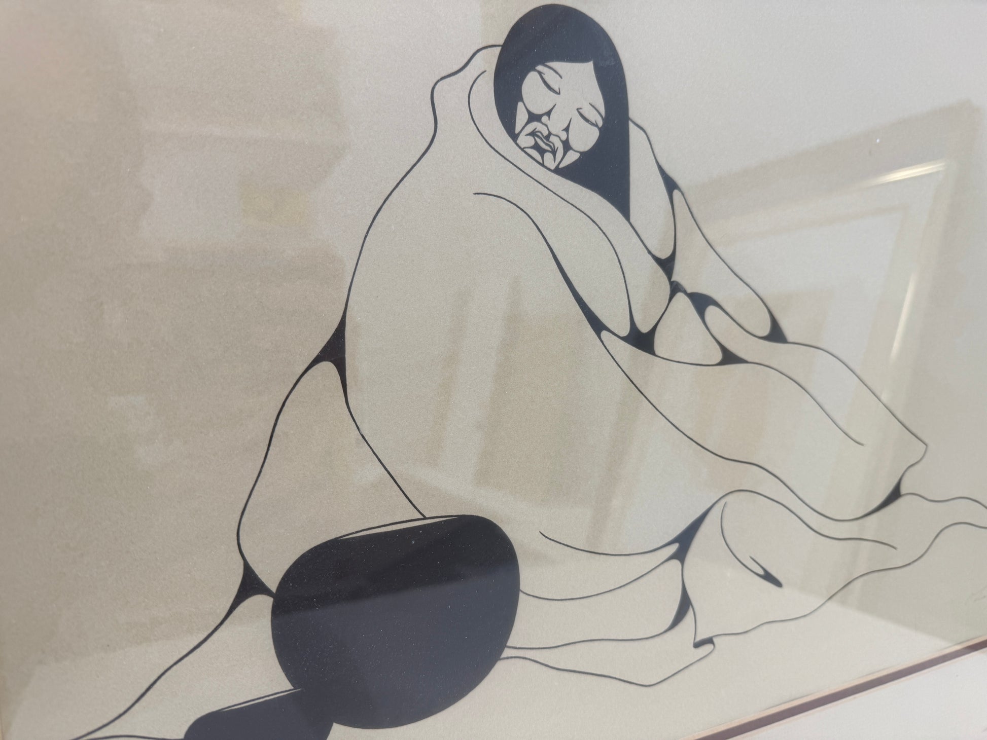 Indian Woman 10/25" is a minimalist black and white drawing of a person with long hair wrapped in a blanket, eyes closed, sitting with a pottery jar nearby. Presented in a 20x27 inch frame, this piece captures serene simplicity and quiet introspection.