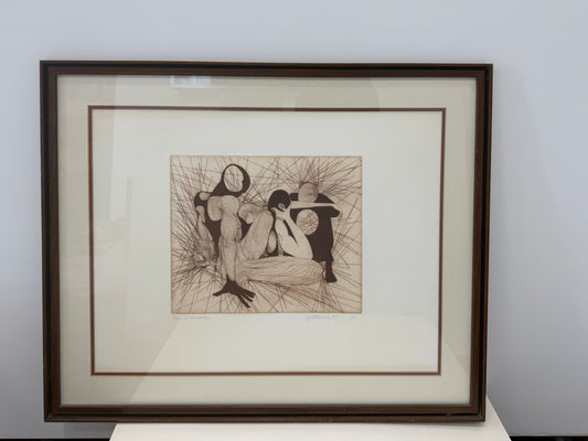Framed abstract artwork titled "La Conversation," featuring five human-like figures with blank circular faces, intertwined and surrounded by radiating lines on a neutral background, displayed against a plain wall.