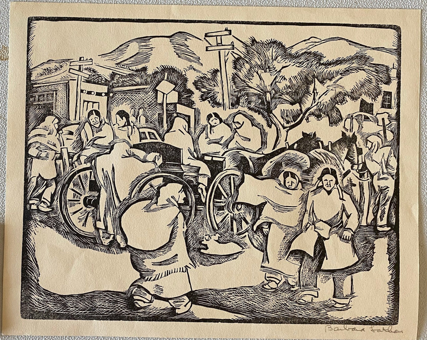 Woodcut print of a historical scene with people and a wheel, displayed on a light gray wall.