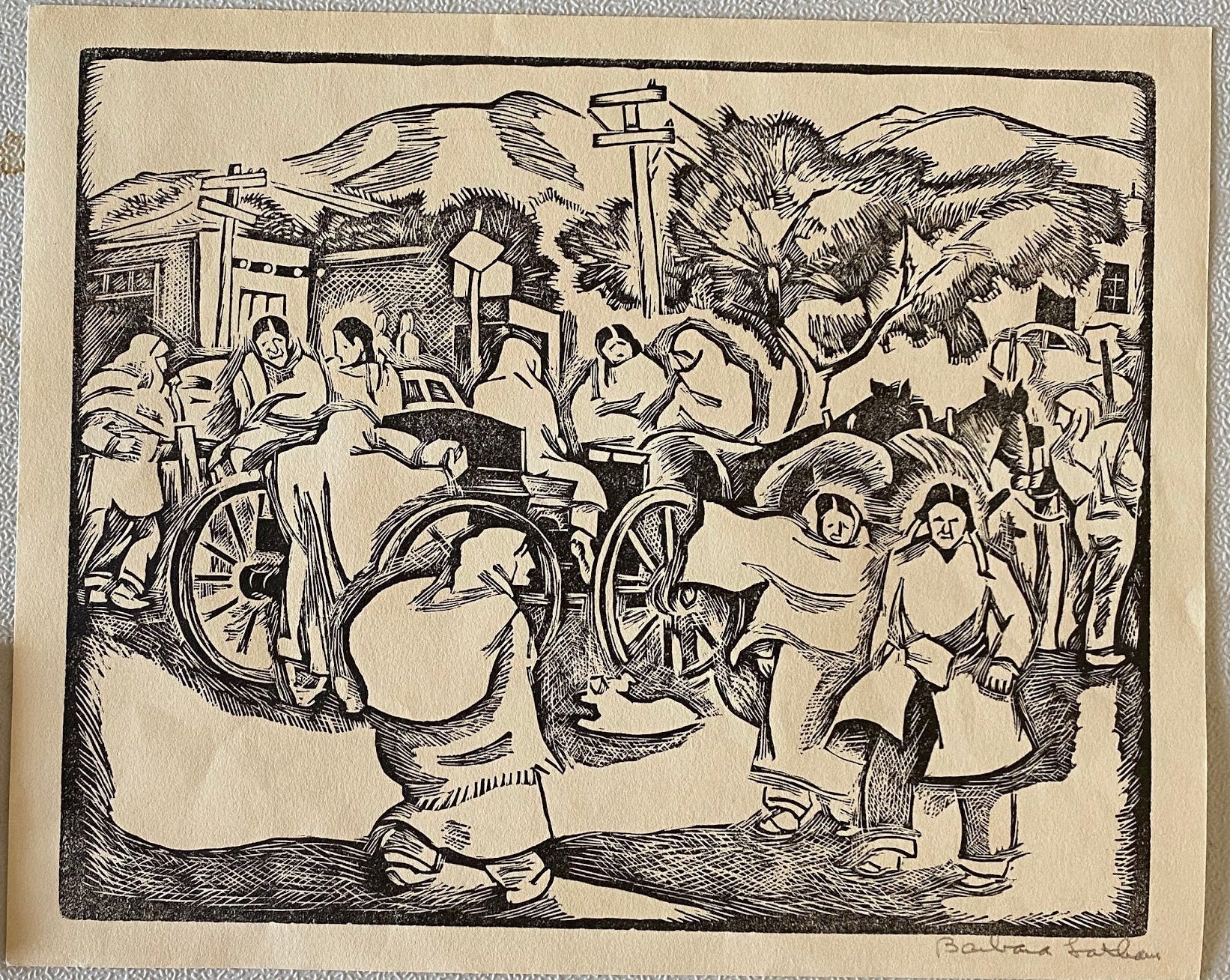 Woodcut print of a historical scene with people and a wheel, displayed on a light gray wall.